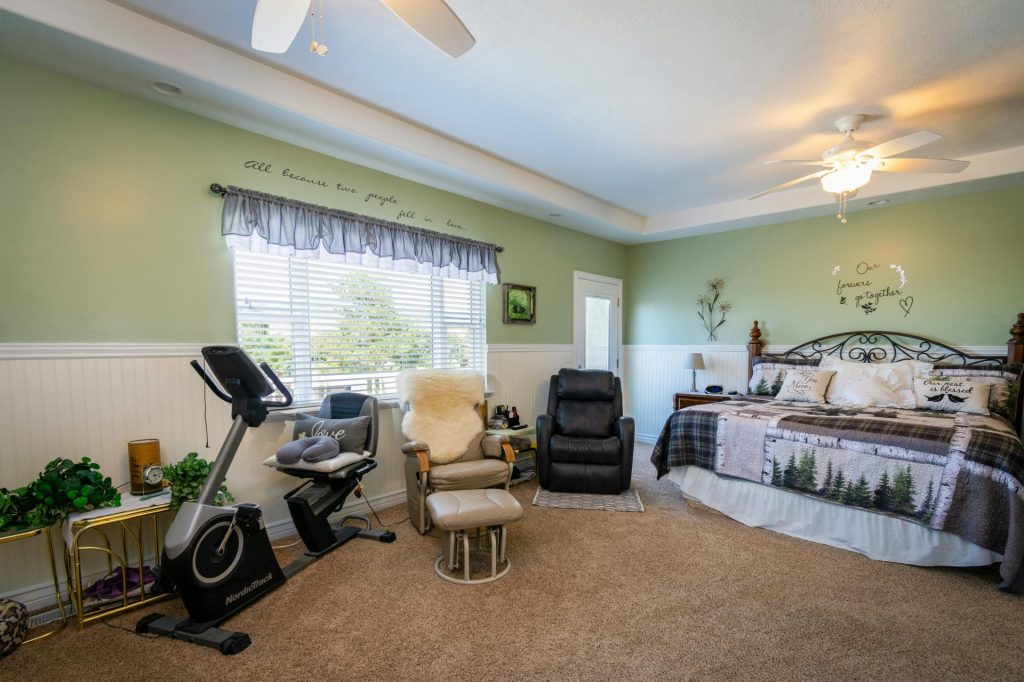 Amplio dormitorio con aparatos de fitness, sillones y una decoración elegante, ideal para relajarse.